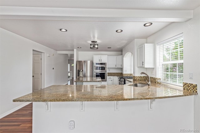 5403 Odessa St, Denver, CO 80249 - kitchen with a sink, appliances with stainless steel finishes, a peninsula, dark wood finished floors, and a breakfast bar area