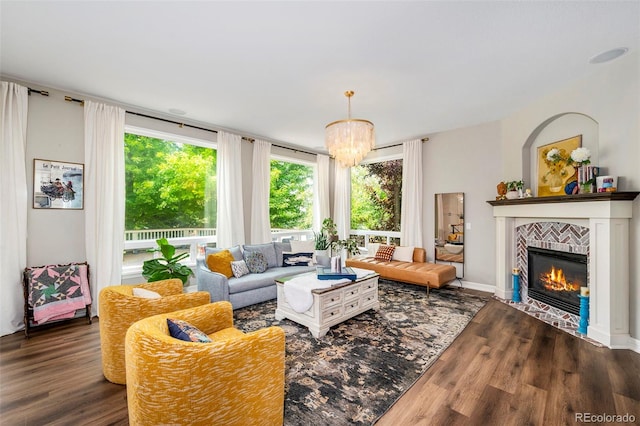 living room featuring a notable chandelier, a tiled fireplace, and dark hardwood / wood-style flooring