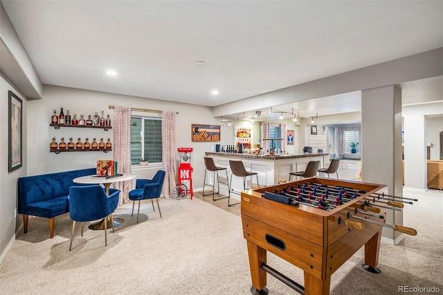 game room with light carpet and bar area