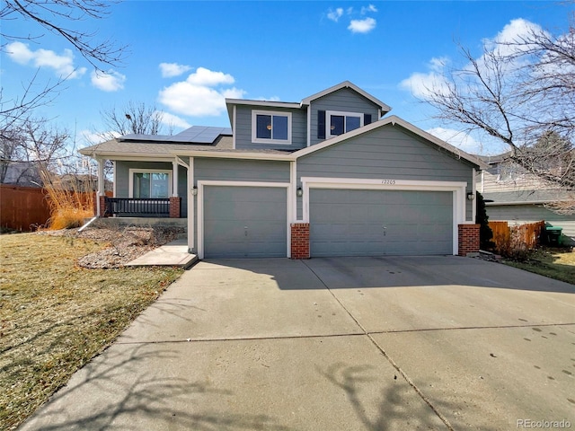 traditional home with driveway, a garage, solar panels, fence, and brick siding