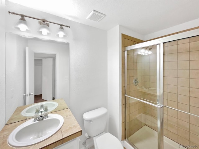 bathroom with toilet, a stall shower, vanity, and visible vents