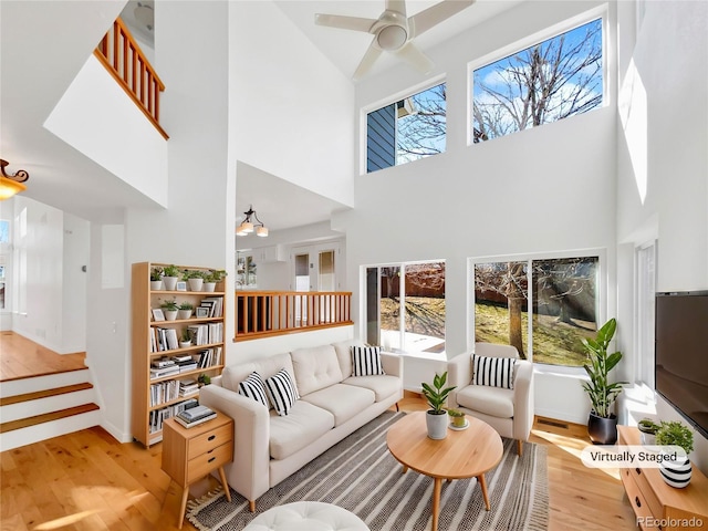 living area with ceiling fan, baseboards, wood finished floors, and a healthy amount of sunlight