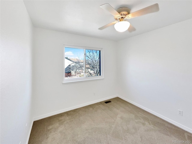 unfurnished room with carpet floors, a ceiling fan, visible vents, and baseboards