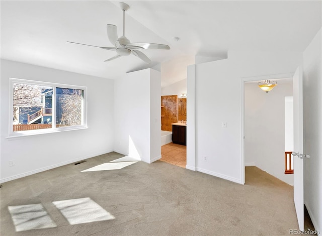 unfurnished bedroom with lofted ceiling, connected bathroom, carpet flooring, visible vents, and baseboards