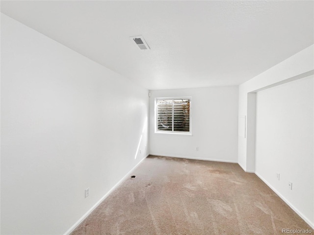 carpeted spare room featuring visible vents and baseboards