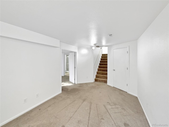 finished below grade area featuring stairs, carpet floors, visible vents, and baseboards