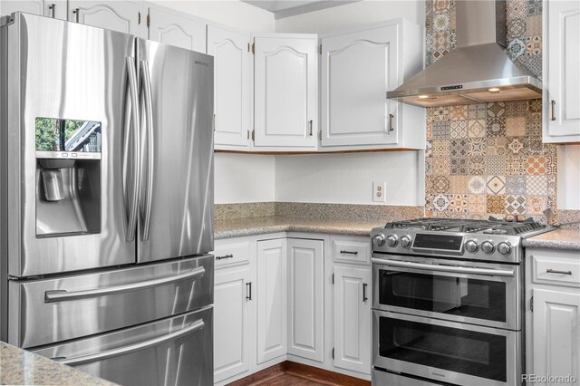 25531 Mosier Cir, Conifer, CO 80433 - kitchen with appliances with stainless steel finishes, wall chimney exhaust hood, white cabinetry, decorative backsplash, and light countertops