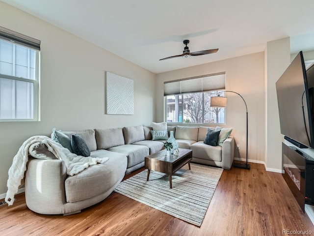 living room with ceiling fan, baseboards, and wood finished floors