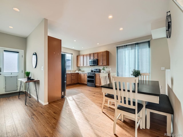 kitchen featuring light wood-style flooring, recessed lighting, appliances with stainless steel finishes, brown cabinetry, and light countertops