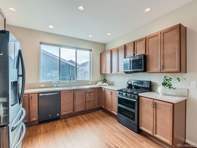 kitchen with light wood-style flooring, a sink, recessed lighting, stainless steel appliances, and light countertops