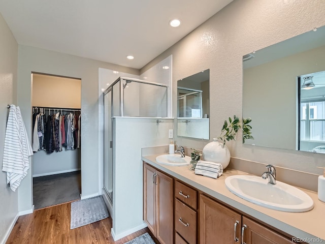 bathroom with a shower stall, wood finished floors, and a sink