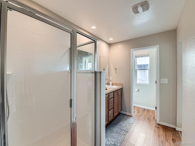 full bath featuring visible vents, baseboards, a stall shower, wood finished floors, and vanity