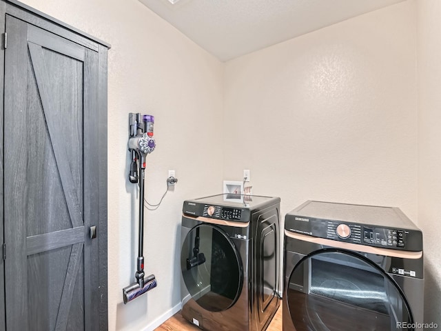 clothes washing area featuring baseboards, light wood finished floors, laundry area, and washer and clothes dryer