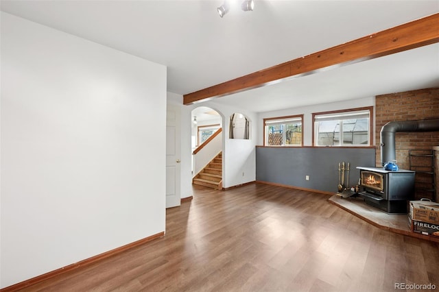 1617 W Boulder St, Colorado Springs, CO 80904 - unfurnished living room with a wood stove, wood finished floors, baseboards, arched walkways, and beam ceiling