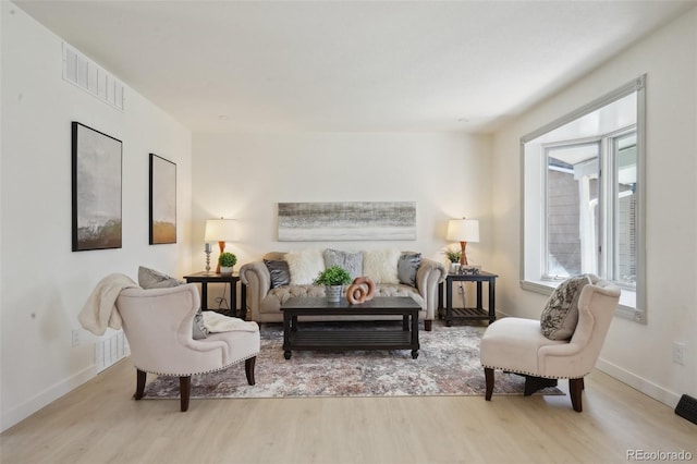 living area with baseboards, wood finished floors, and visible vents