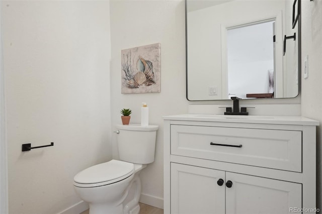 half bath featuring toilet, baseboards, and vanity
