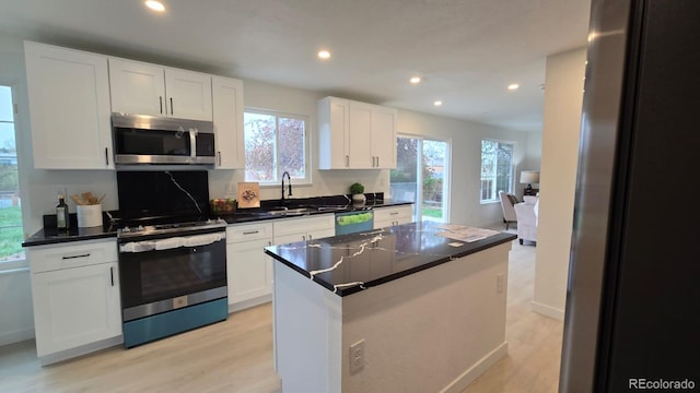 kitchen with dark countertops, appliances with stainless steel finishes, recessed lighting, and light wood-type flooring