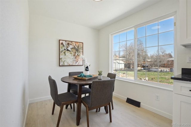 dining room featuring baseboards, light wood-style floors, and visible vents
