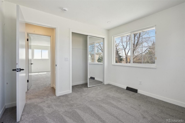 unfurnished bedroom featuring carpet floors, baseboards, visible vents, and a closet
