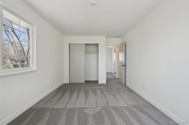 unfurnished bedroom featuring baseboards, carpet, and a closet