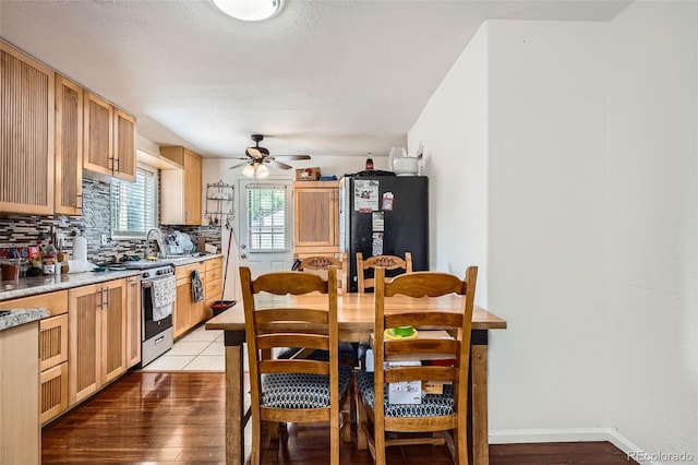 6736 Grove St, Denver, CO 80221 - kitchen with freestanding refrigerator, stainless steel range with gas stovetop, tasteful backsplash, ceiling fan, and light countertops