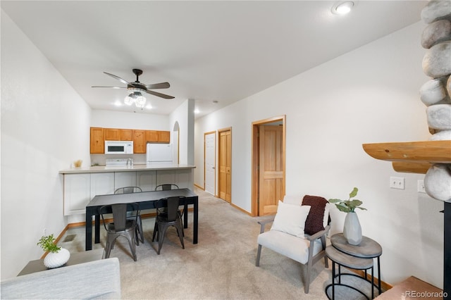 dining area with light carpet, ceiling fan, and baseboards