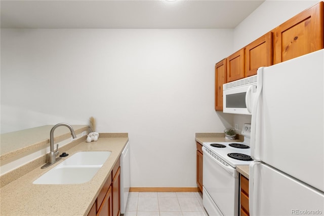 kitchen featuring white appliances, light tile patterned floors, baseboards, brown cabinets, and a sink