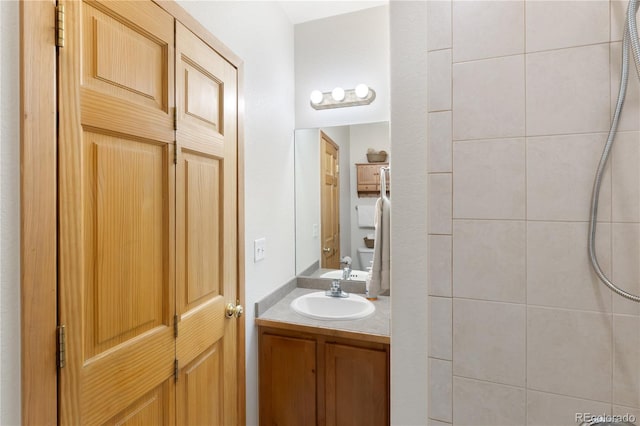 full bath featuring tiled shower and vanity