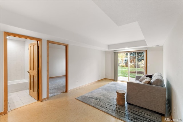 living room with a tray ceiling and baseboards