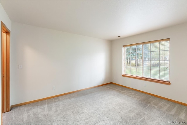 unfurnished room with light colored carpet and baseboards