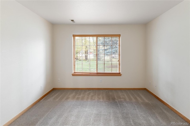 carpeted spare room with visible vents and baseboards