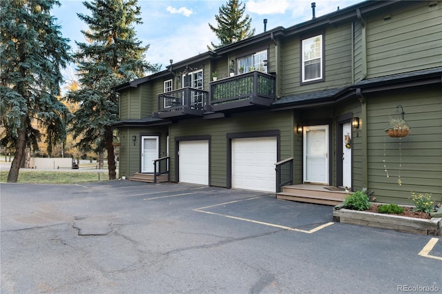 view of front of property featuring a garage, driveway, and a balcony