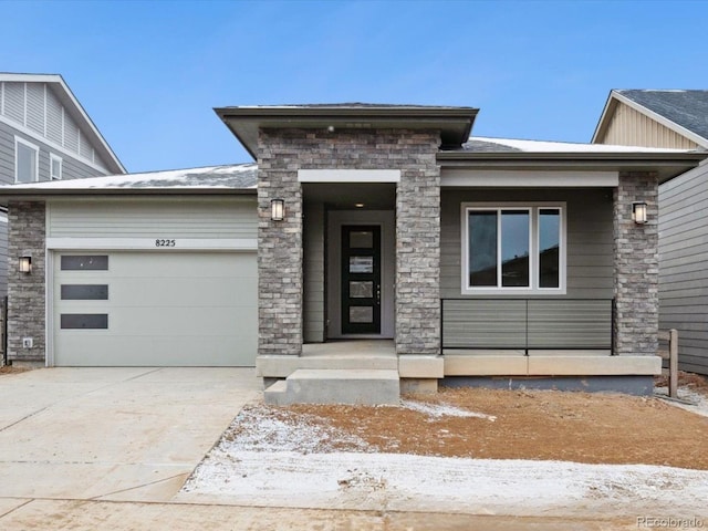 prairie-style house featuring an attached garage, stone siding, and driveway