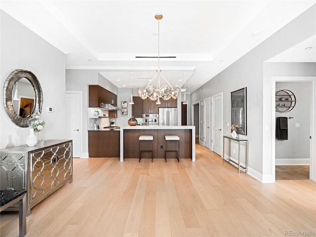 kitchen featuring dark brown cabinetry, stainless steel appliances, a raised ceiling, and light hardwood / wood-style floors