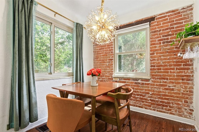 dining room featuring a wealth of natural light, a chandelier, hardwood / wood-style flooring, and brick wall