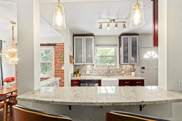 kitchen featuring a kitchen breakfast bar, track lighting, sink, tasteful backsplash, and stainless steel dishwasher