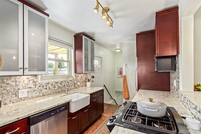 kitchen featuring dishwasher, light stone countertops, backsplash, track lighting, and hardwood / wood-style flooring