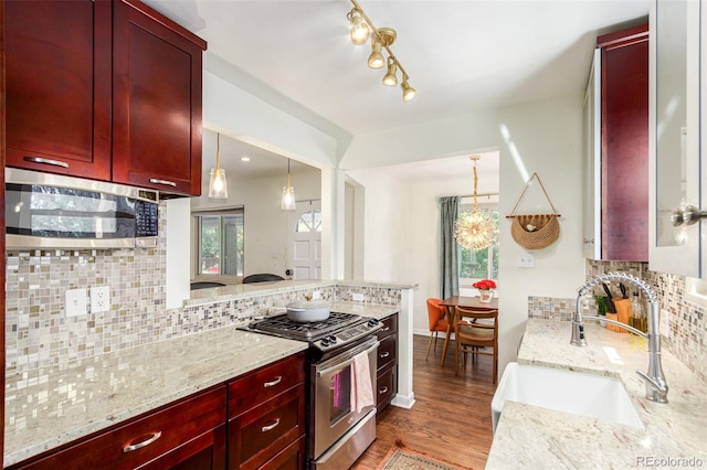 kitchen featuring decorative backsplash, hardwood / wood-style floors, appliances with stainless steel finishes, light stone countertops, and sink