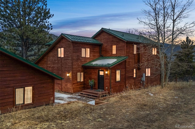 front of property at dusk featuring a standing seam roof and metal roof