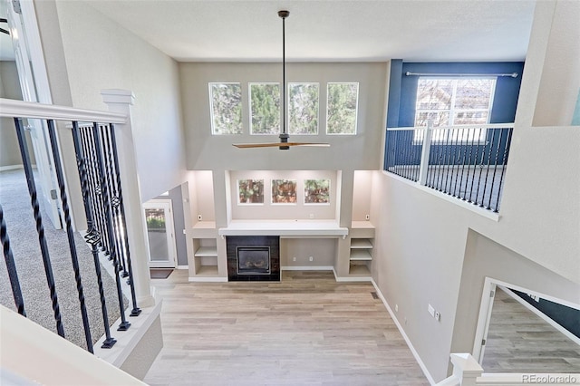 2901 Madison Ln, Broomfield, CO 80023 - unfurnished living room featuring wood finished floors, healthy amount of natural light, a high ceiling, a tiled fireplace, and baseboards