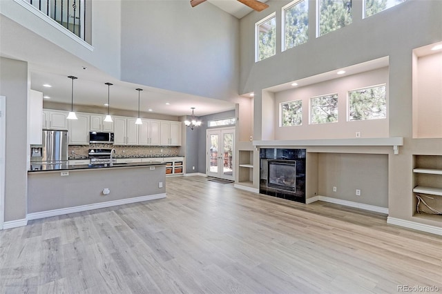 2901 Madison Ln, Broomfield, CO 80023 - unfurnished living room with a towering ceiling, light wood-type flooring, a sink, a fireplace, and a ceiling fan
