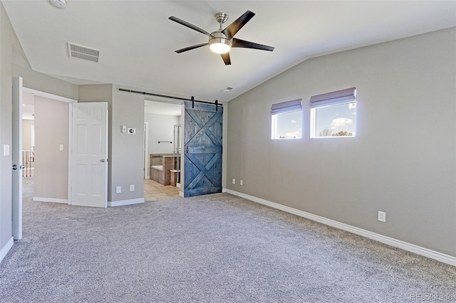 2901 Madison Ln, Broomfield, CO 80023 - unfurnished bedroom featuring a barn door, light colored carpet, baseboards, connected bathroom, and vaulted ceiling