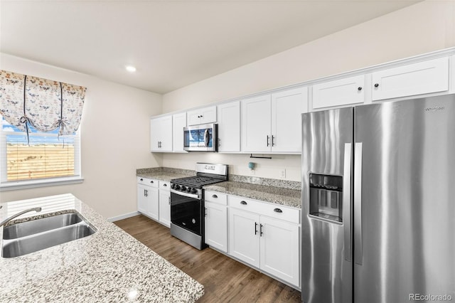 kitchen with dark wood-type flooring, stainless steel appliances, sink, light stone countertops, and white cabinets