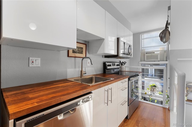 kitchen with white cabinets, butcher block countertops, sink, and stainless steel appliances