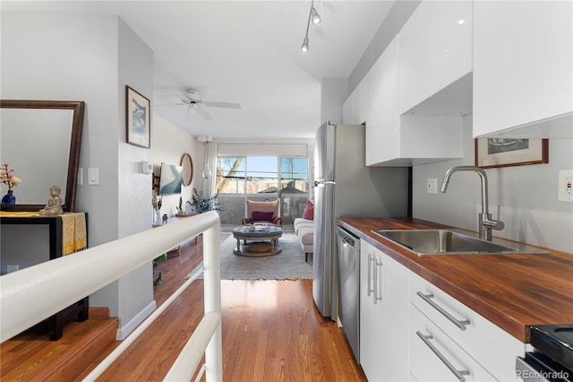 kitchen with white cabinetry, ceiling fan, butcher block counters, and sink