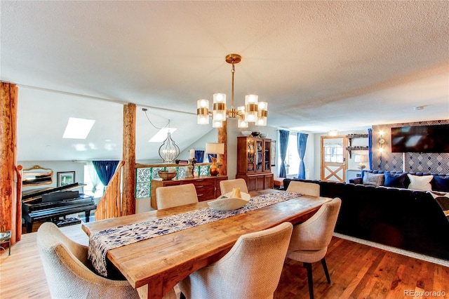 233 Perry Park Ave, Larkspur, CO 80118 - dining room featuring a chandelier, wood finished floors, a skylight, a textured ceiling, and lofted ceiling