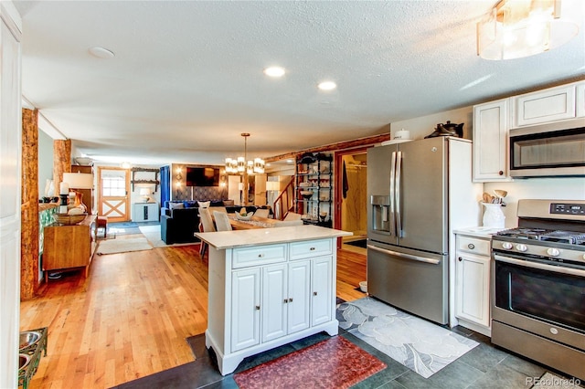 233 Perry Park Ave, Larkspur, CO 80118 - kitchen with appliances with stainless steel finishes, light countertops, white cabinets, a chandelier, and a textured ceiling