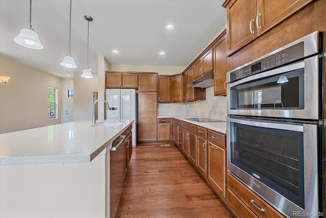1130 Summit View Dr, Louisville, CO 80027 - kitchen featuring appliances with stainless steel finishes, under cabinet range hood, wood finished floors, brown cabinets, and a sink