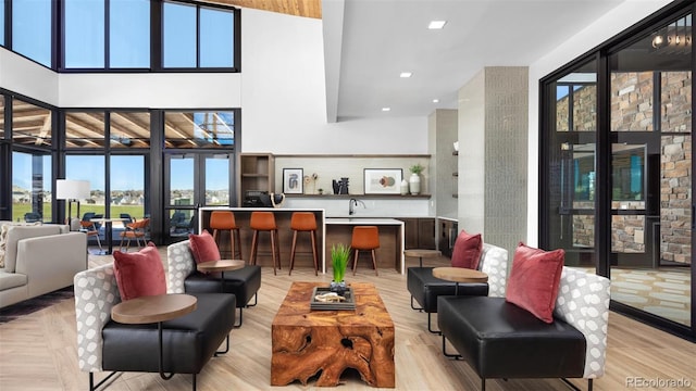 interior space featuring recessed lighting, a high ceiling, plenty of natural light, and light wood-style floors