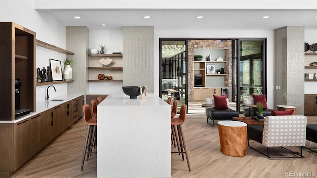 kitchen with a sink, light countertops, a kitchen breakfast bar, and open shelves